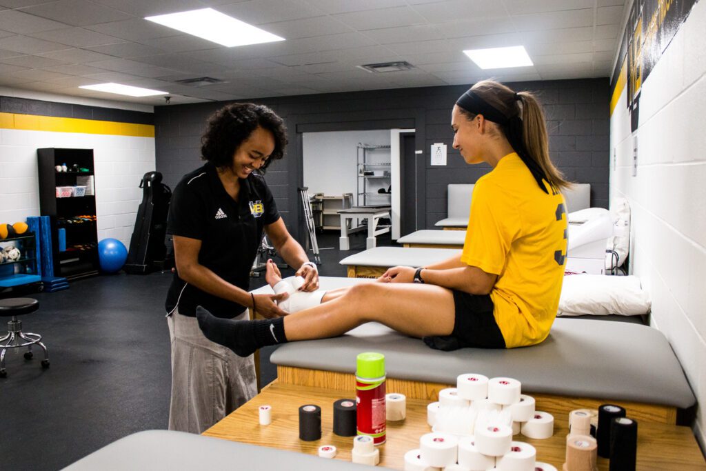 An athletic trainer wraps an athletes ankle in the training room within the Physical Activities Center.