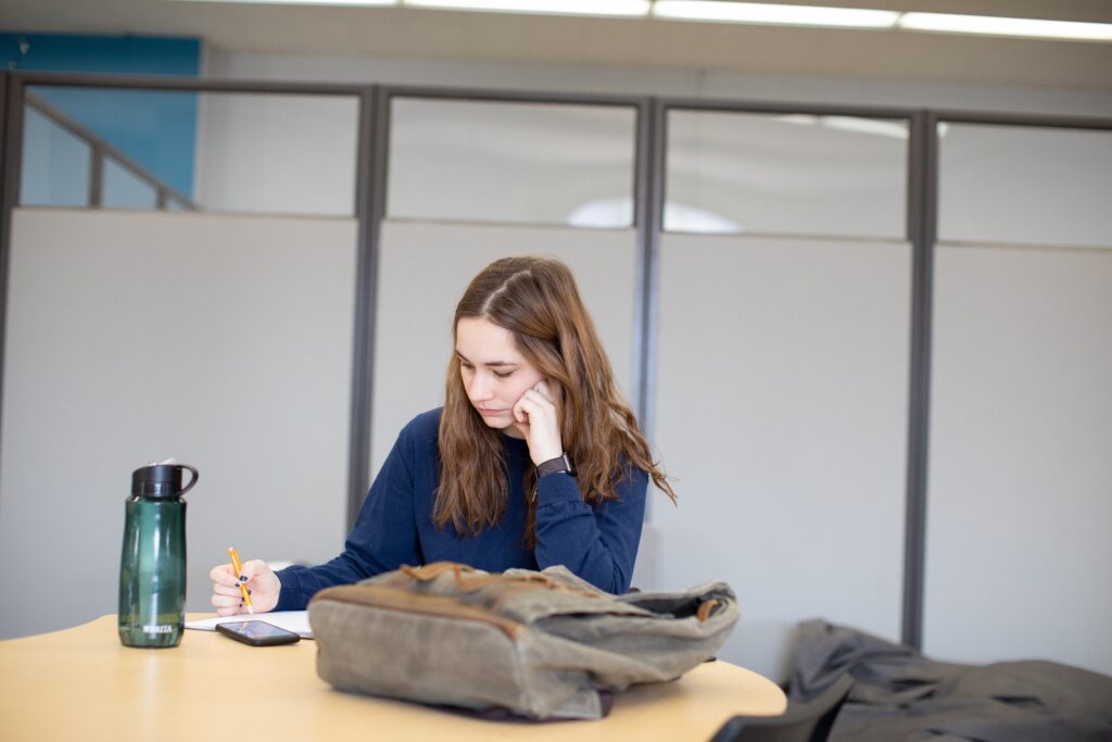 Student reads over notes at a table in the library.