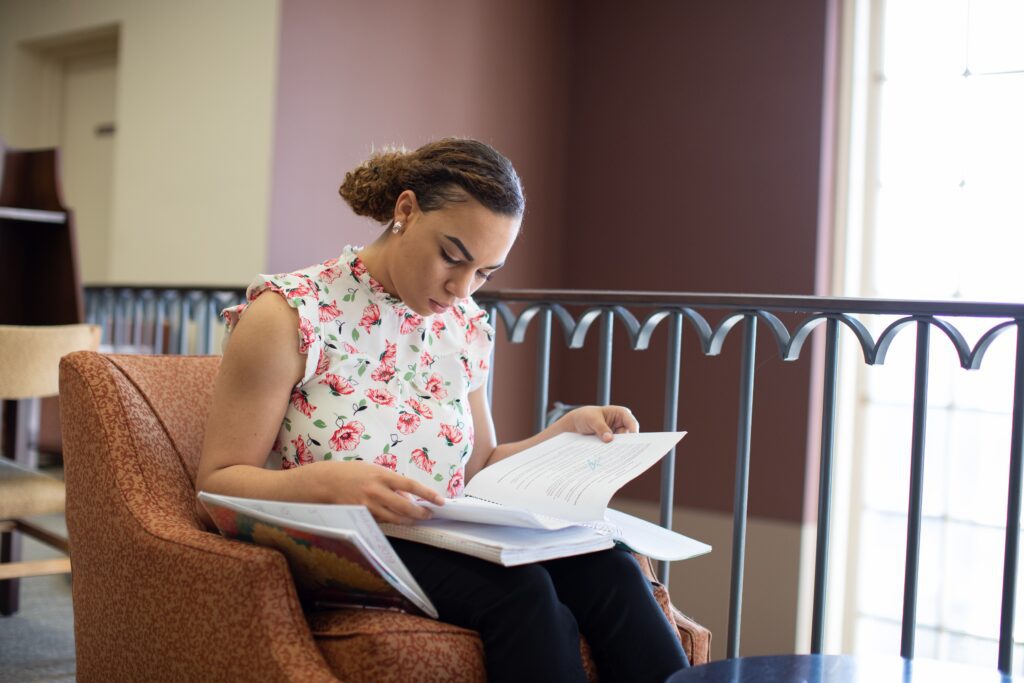 A student reads over their textbook in the library.