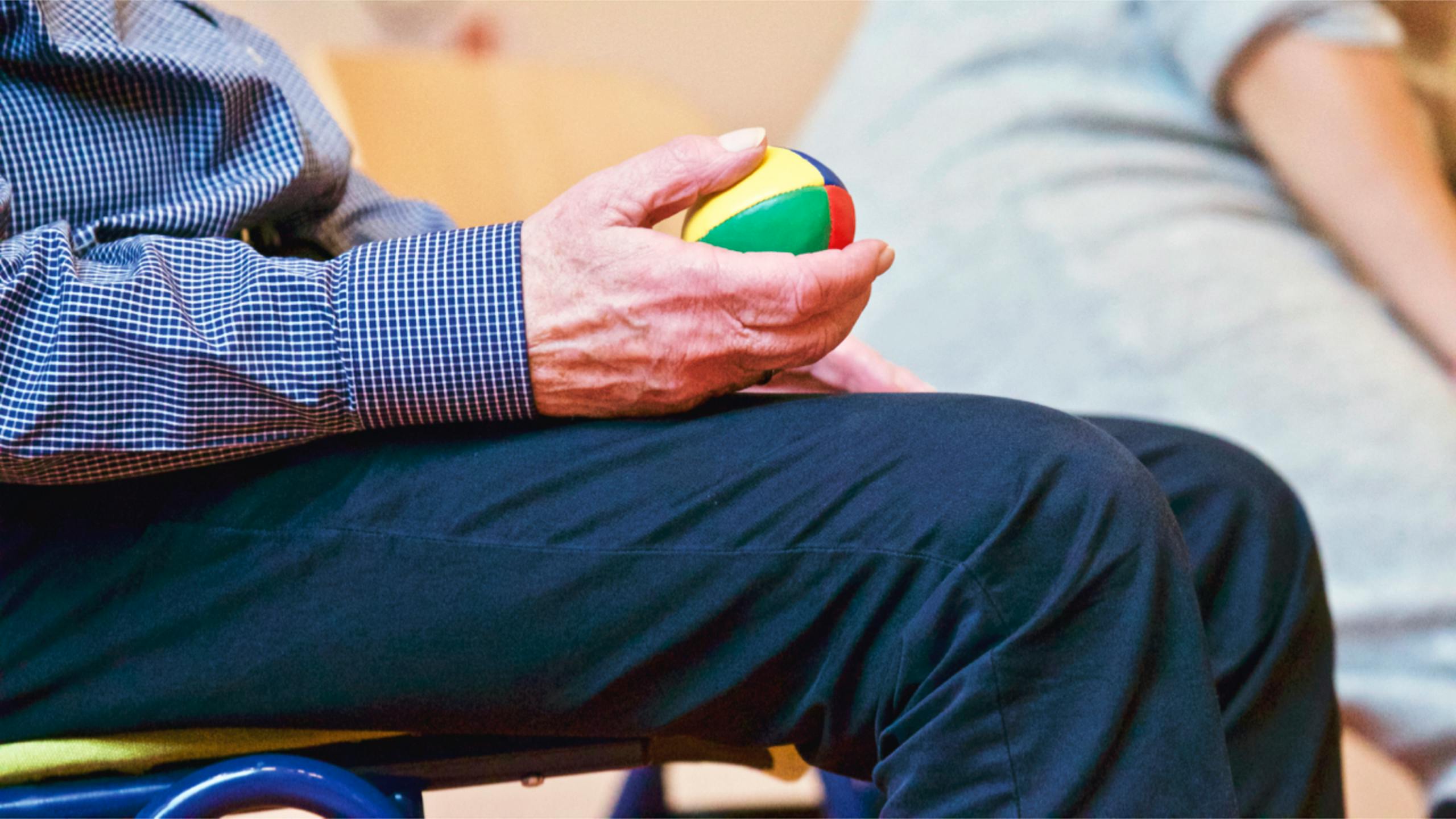 An elderly person squeezes a ball as part of therapy
