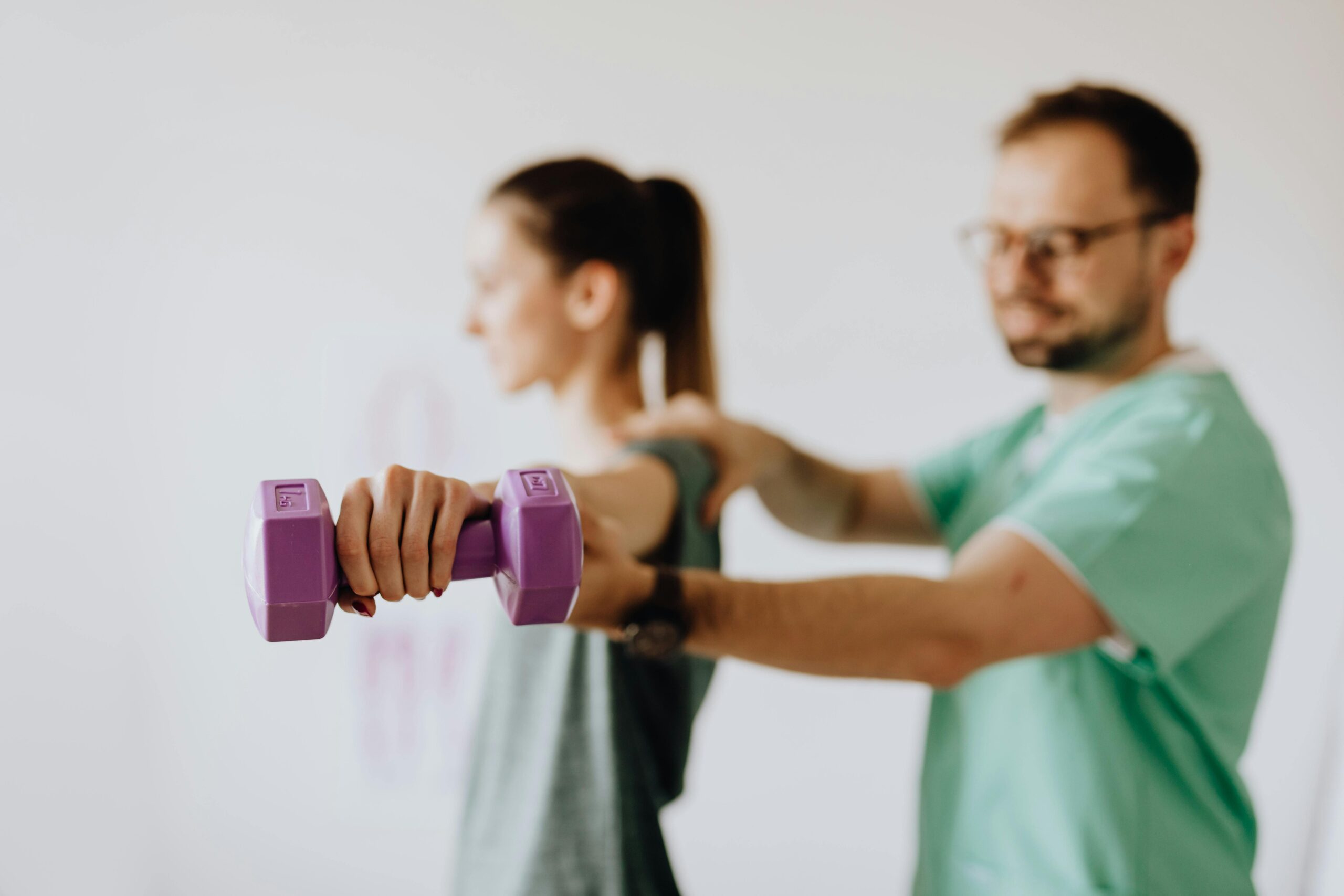 A physical therapist helps a woman lift weights
