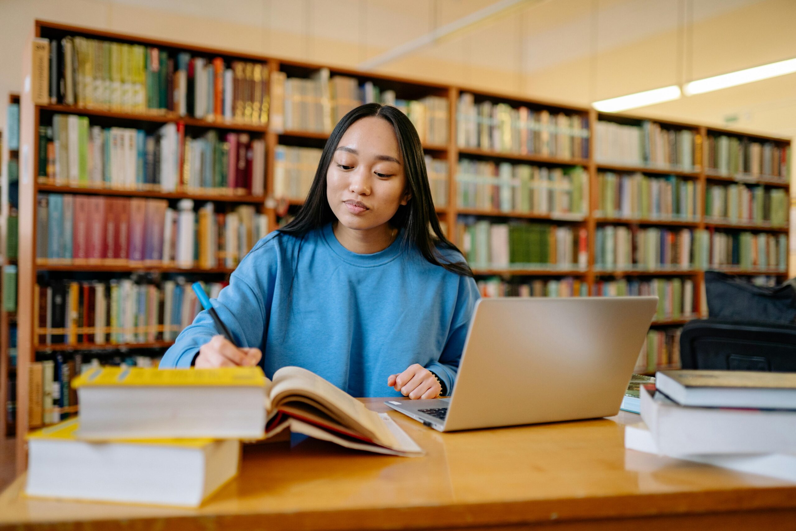 A young woman reads a textbook and takes notes