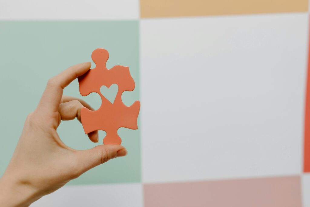A person holds a puzzle piece with a heart