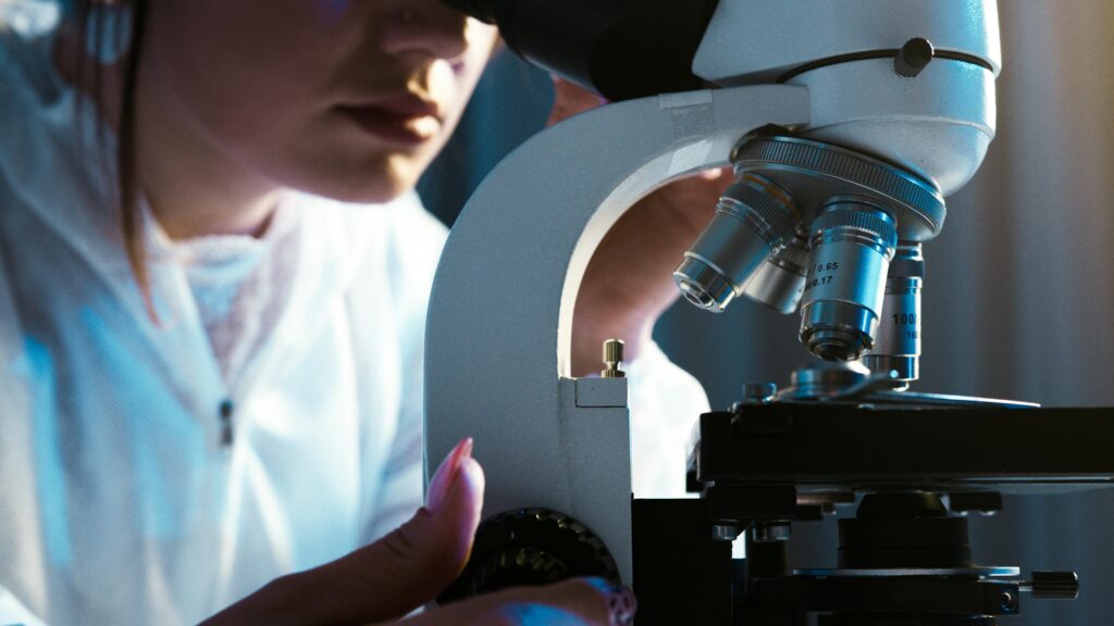 A scientist looks into a microscope.