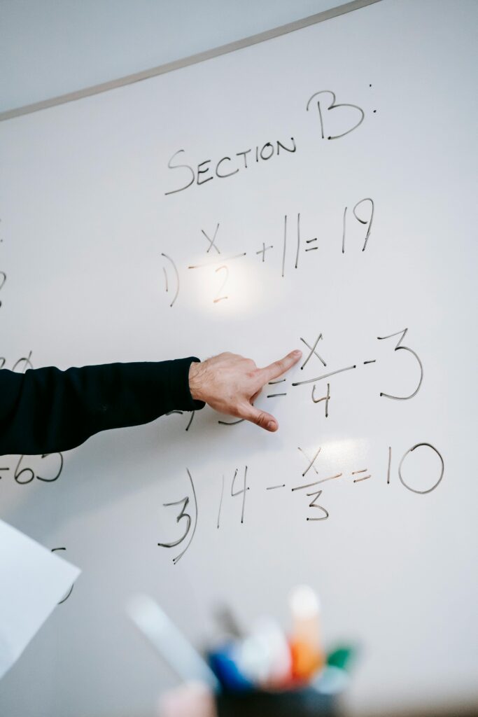 A professor points to math problems on a board