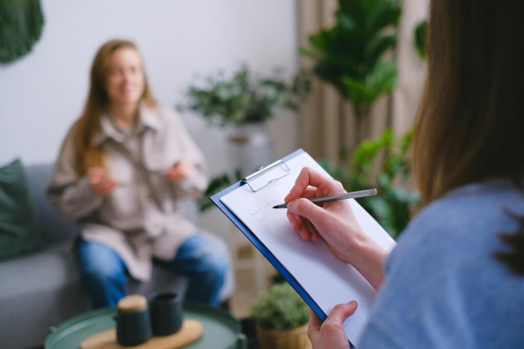 A psychiatrist takes notes as her patient talks.