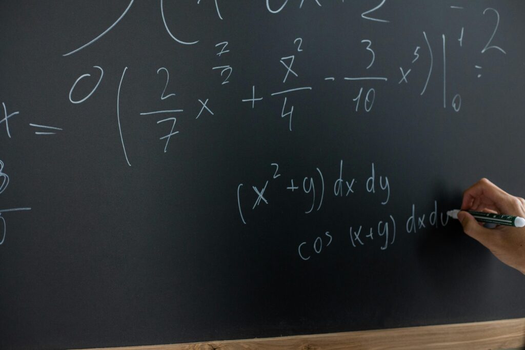 Math equations being written out on a chalkboard.