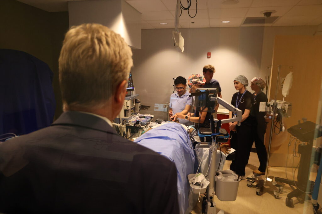 A guest watches the action in the operating room through a two-way mirror