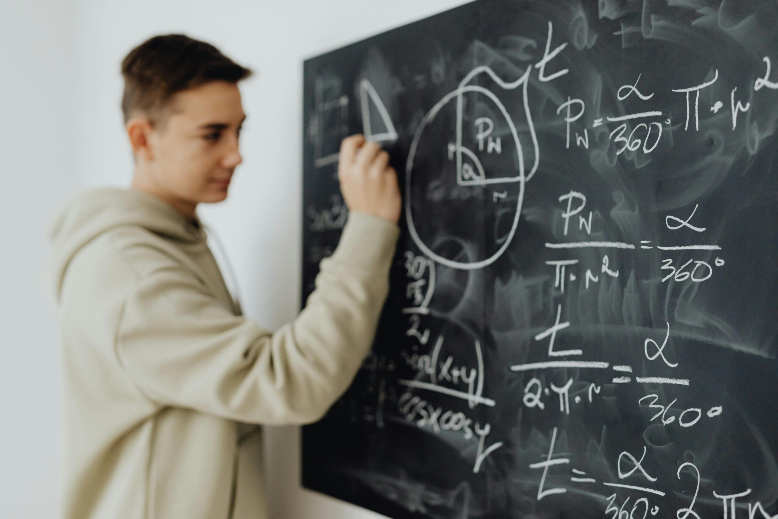 A high school boy writes complex math problems on the chalkboard