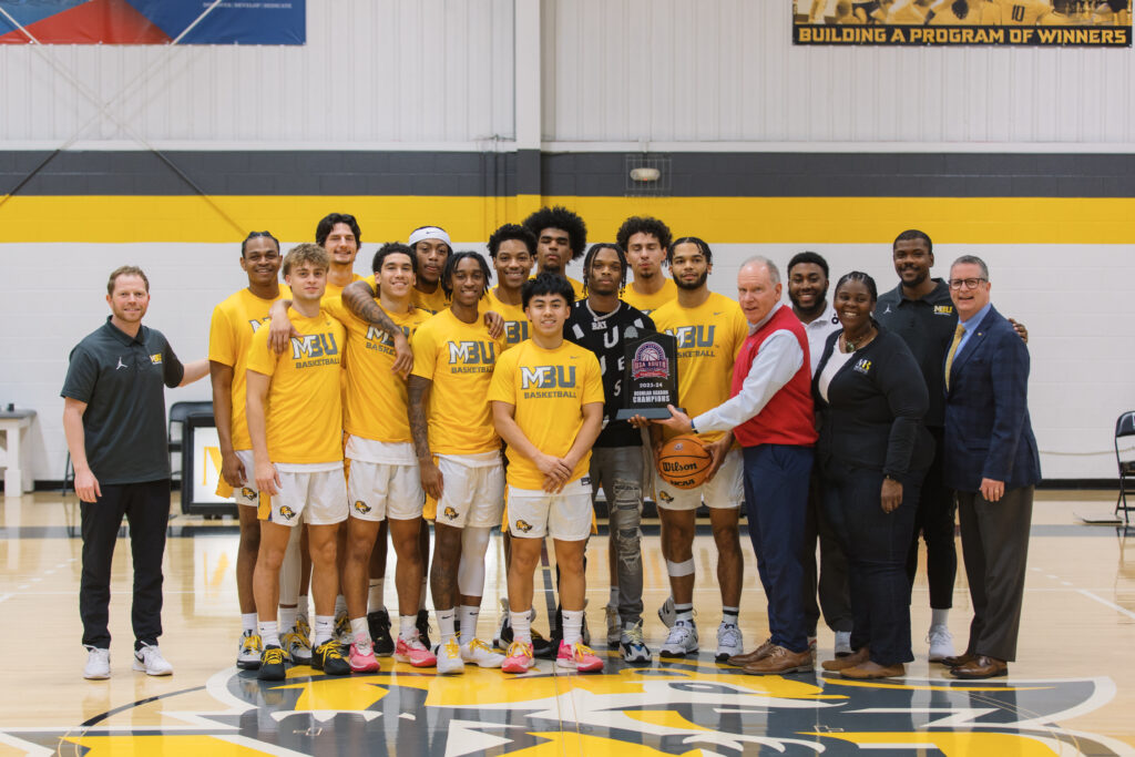 The 2024 MBU Men's basketball team poses with their trophy.