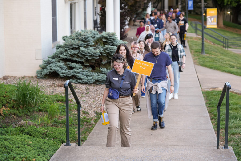 A young woman leading a large group of students on a campus tour