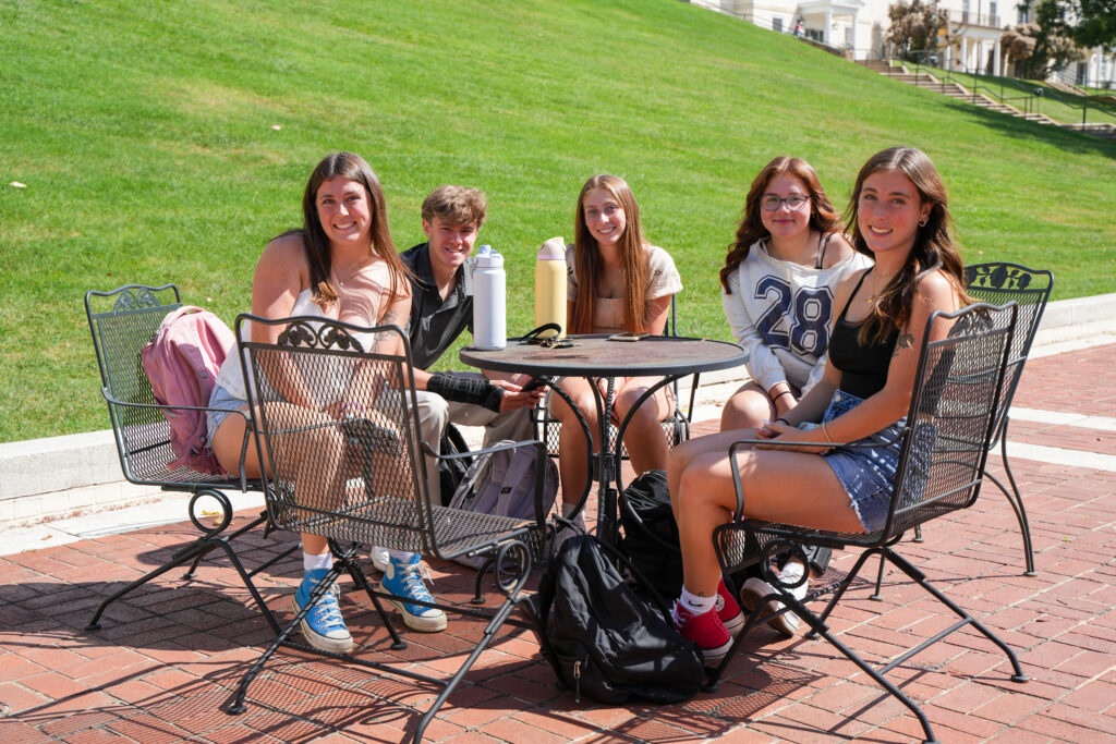 Students sit together at an outside patio table on the first day of classes, 2025.