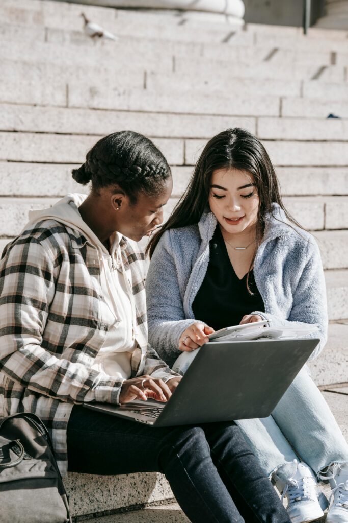 Two college students work on a laptop