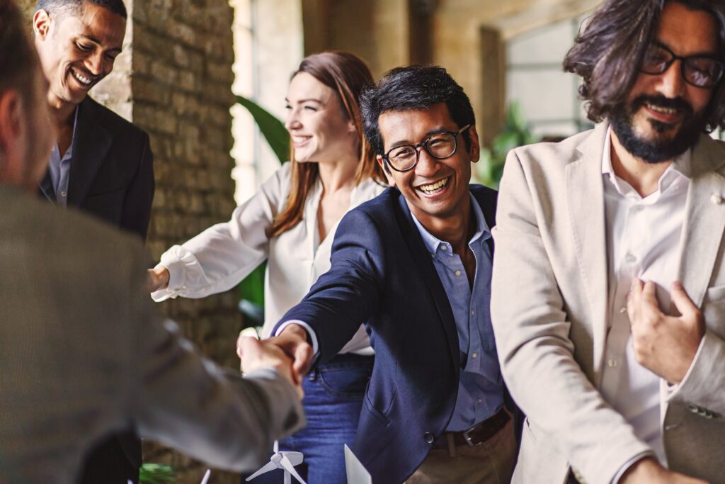 Group of diverse professionals celebrating with a handshake at a corporate event, embodying teamwork and achievement.