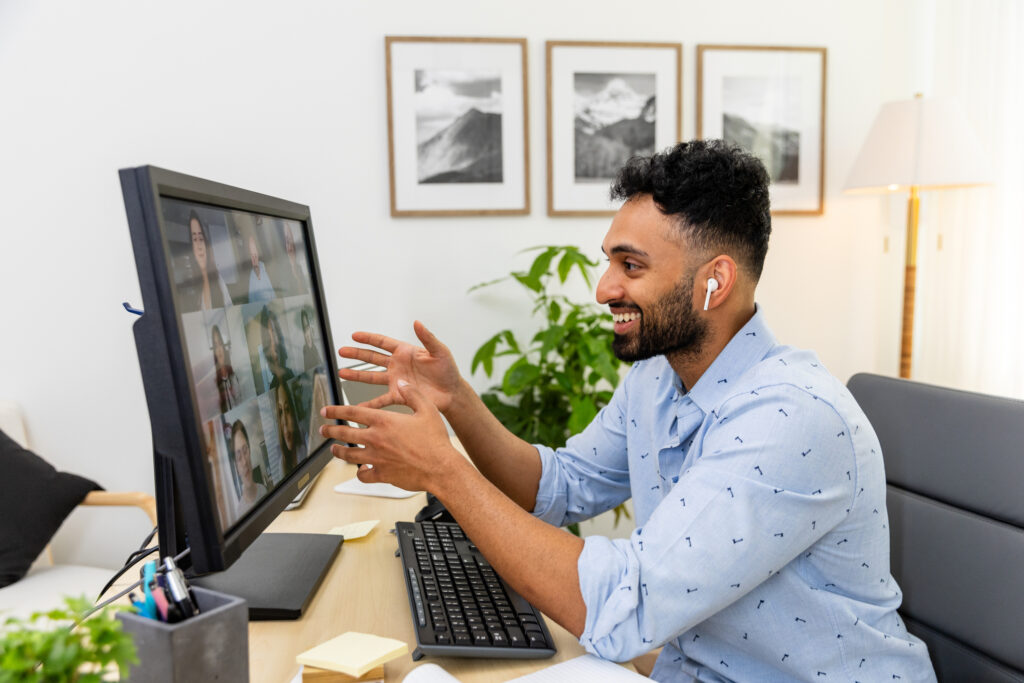 Cheerful man in casual wear enjoys a video conference call with his team.  Wireless technology and teamwork.