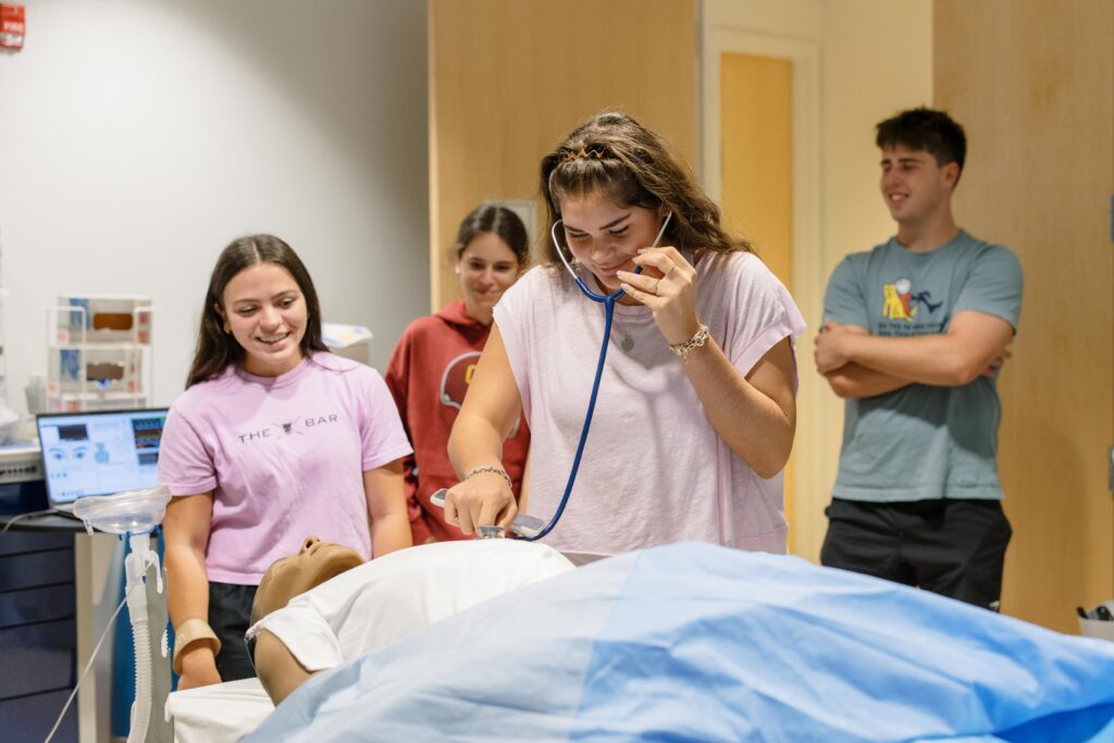 Four Health and Science Neighborhood Students perform medical tests on a dummy