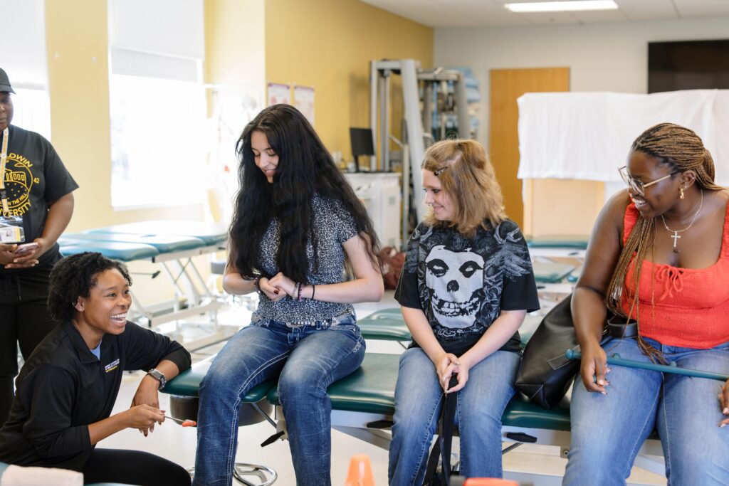 Three Health and Science Neighborhood students practice occupational therapy techniques with a trainer.