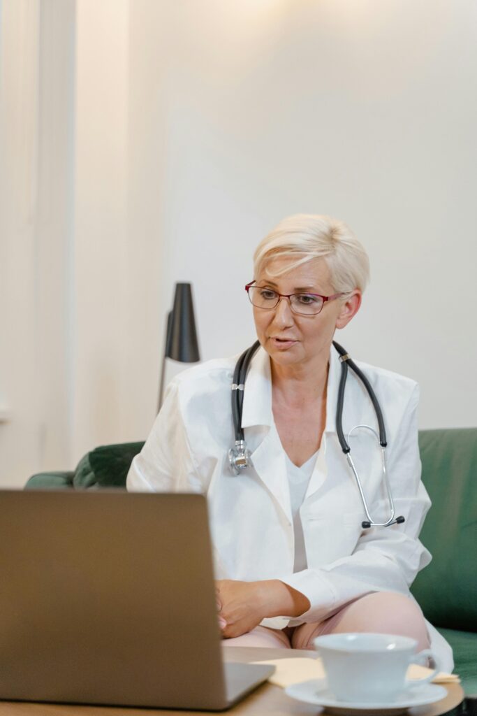 A nurse conducts a telehealth appointment via laptop.