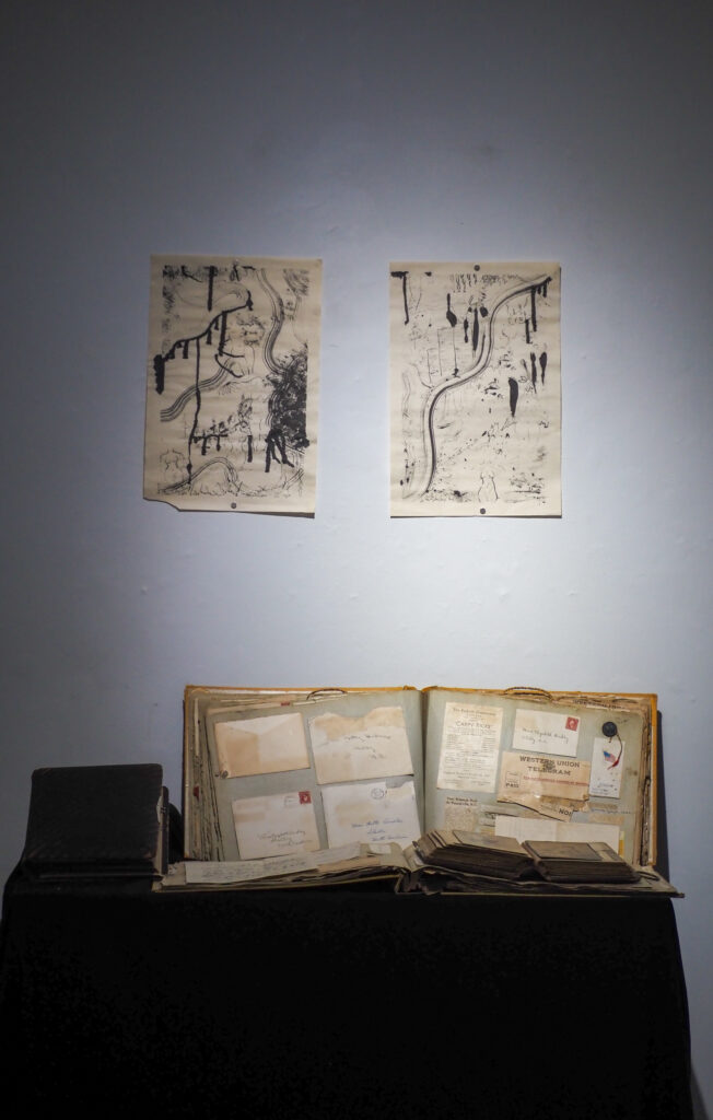 Dramatic lighting showcasing an album of envelopes on a table with drawings on the wall above it