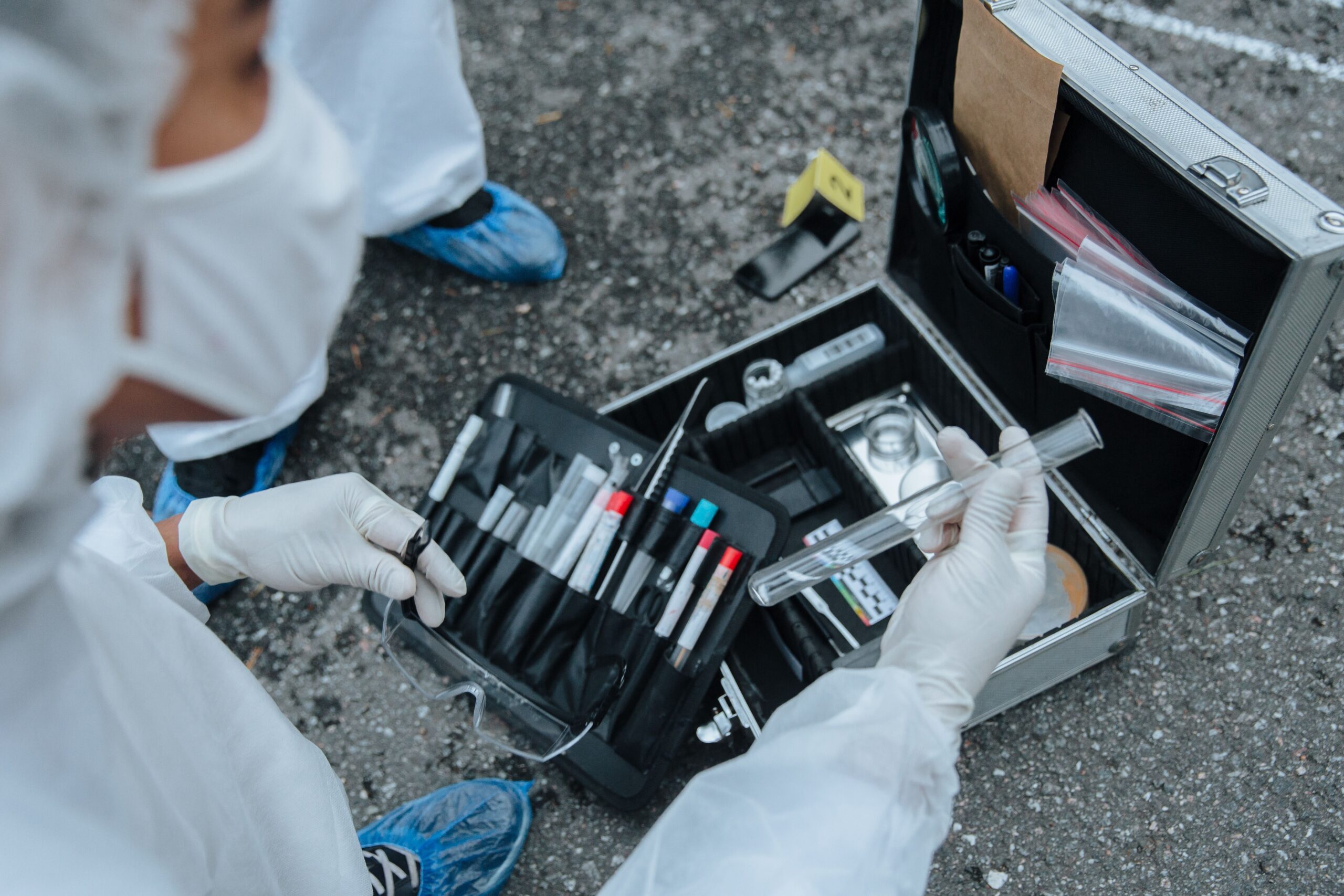 A forensic science technician examines evidence on the road